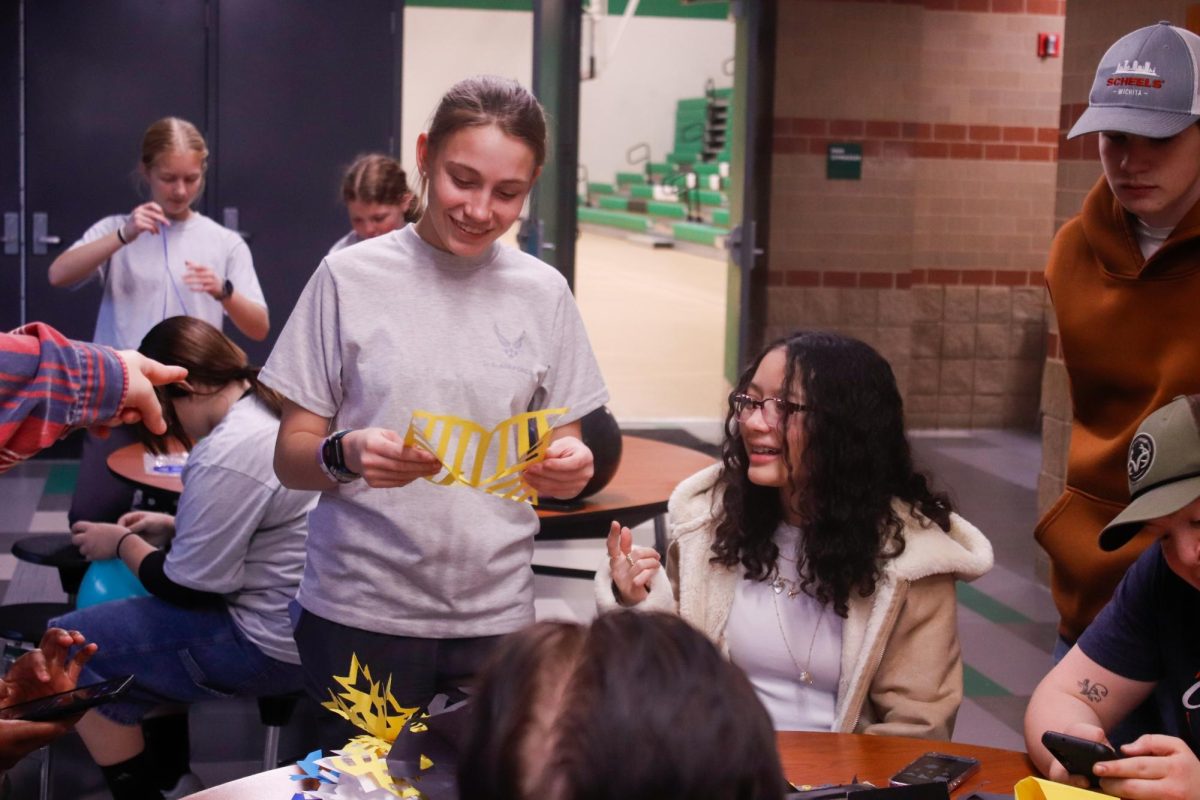 Students laugh together as they cut out paper snowflakes.