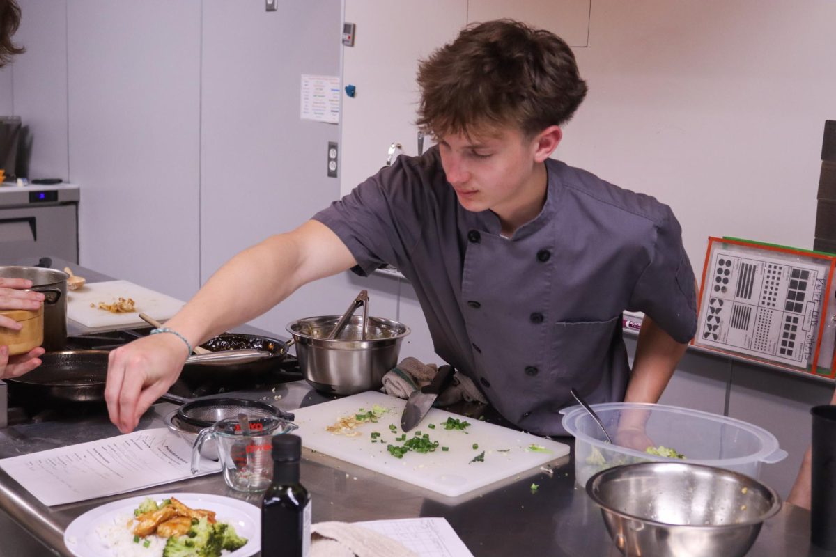 Student sprinkles rice onto a dish. 