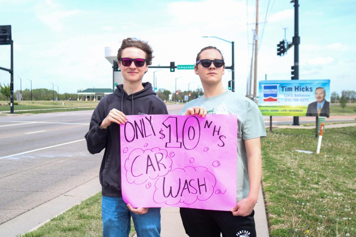 NHS members hold up car wash sign. 