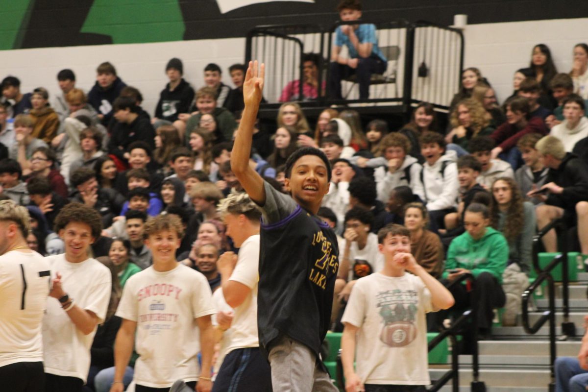A student waves to the crowd after scoring the half court shot.  